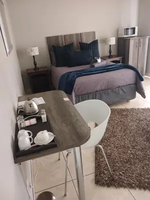 a bedroom with a bed and a table and a bed at Blue Sparrow Guest House in Middelburg