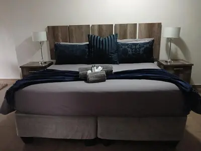 a bedroom with a large bed with two lamps at Blue Sparrow Guest House in Middelburg