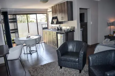 a kitchen and living room with a chair and a table at Blue Sparrow Guest House in Middelburg