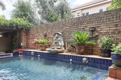 a swimming pool with a fountain in front of a brick wall at The Monte Carlo in Centurion