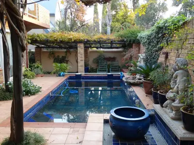 a swimming pool in a garden with a pergola at The Monte Carlo in Centurion