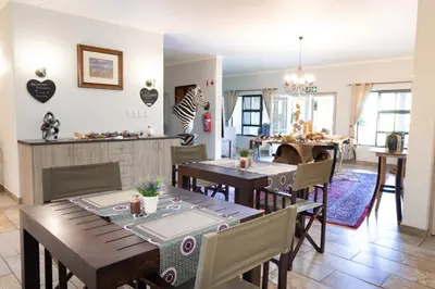 a kitchen and dining room with wooden tables and chairs at The Belgium Inn in Hoedspruit