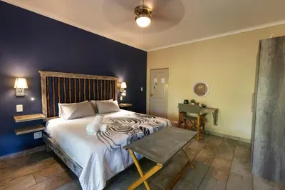a bedroom with a large bed and a table at The Belgium Inn in Hoedspruit
