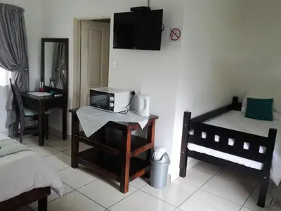 a bedroom with two beds and a tv on the wall at Guest House Mamma Mia in Nelspruit