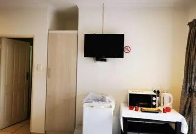 a living room with a tv on the wall and a table at Guest House Mamma Mia in Nelspruit