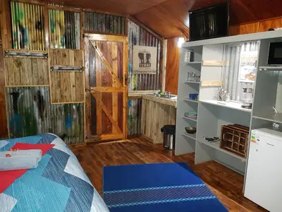 a room with a bed and a kitchen with a door at Thandamanzi Self Catering in Sabie