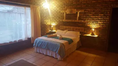a bedroom with a bed and a brick wall at Thandamanzi Self Catering in Sabie