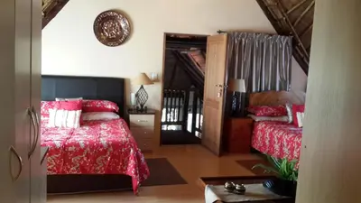 a bedroom with a red bed and a couch at The Cedars Bed and Breakfast in Centurion