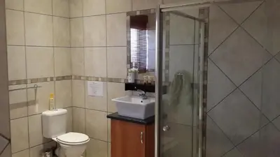 a bathroom with a toilet and a sink and a shower at The Cedars Bed and Breakfast in Centurion