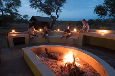 a group of people sitting around a fire pit at Buffelshoek Tented Camp in Manyeleti Game Reserve