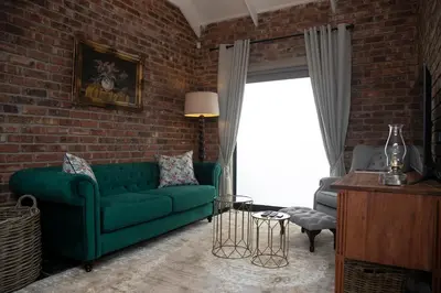 a living room with a green couch and a brick wall at Tarry-Stone Cottages in Dullstroom