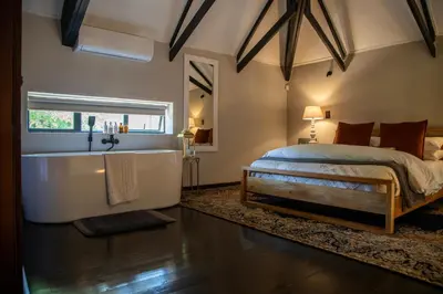 a bedroom with a large bed and a bath tub at Tarry-Stone Cottages in Dullstroom