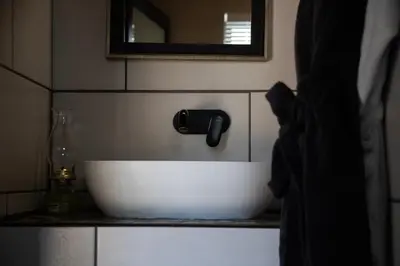 a white sink in a bathroom with a mirror at Tarry-Stone Cottages in Dullstroom