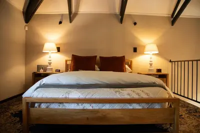 a bedroom with a bed with two lamps on both sides at Tarry-Stone Cottages in Dullstroom