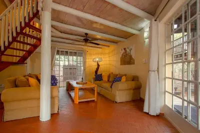 a living room with two couches and a table at Treetops Marloth Park in Marloth Park