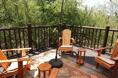 a group of chairs sitting on a deck with an umbrella at Treetops Marloth Park in Marloth Park