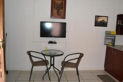 a table and two chairs and a television on a wall at Komati Friends in Komatipoort