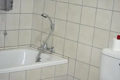 a bath tub with a shower head in a bathroom at Komati Friends in Komatipoort