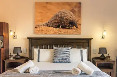 a bedroom with a bed with a pulture painting on the wall at Mawusi Bush Lodge in Hoedspruit