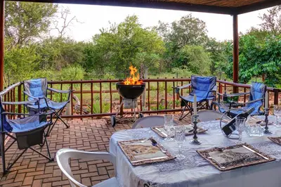 a table and chairs on a patio with a fire pit at Mawusi Bush Lodge in Hoedspruit