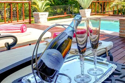 a bottle of wine and two glasses on a table at Mawusi Bush Lodge in Hoedspruit
