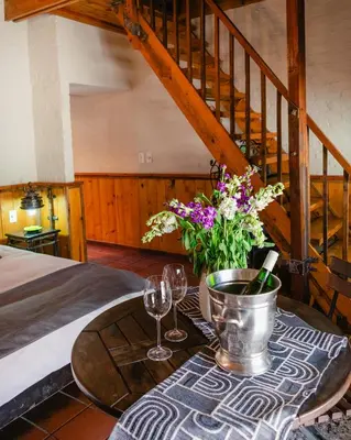 a table with two wine glasses and flowers on it at Anglers Court in Dullstroom