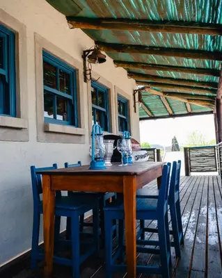 a wooden table and blue chairs on a patio at Anglers Court in Dullstroom