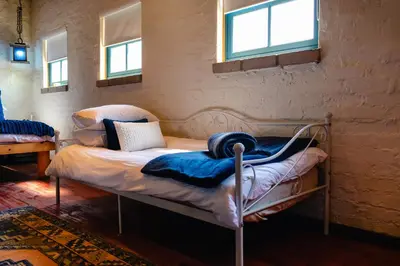 a bedroom with a bed in a room with windows at Anglers Court in Dullstroom