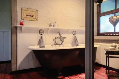 a bathroom with a bath tub with a sink at Anglers Court in Dullstroom