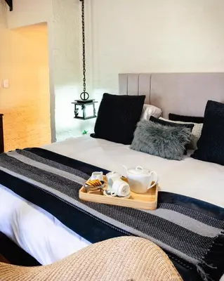 a bed with a tray of food on it at Anglers Court in Dullstroom
