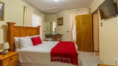 a bedroom with a large bed with a red blanket at Gannet Place Guest House in Hazyview