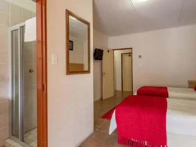 a bedroom with a bed with a red blanket and a mirror at Gannet Place Guest House in Hazyview
