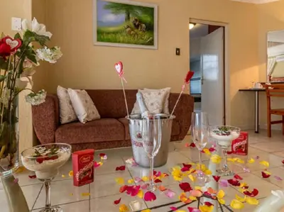 a living room with a table with flowers and wine glasses at Gannet Place Guest House in Hazyview