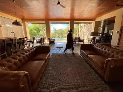 a person walking through a room with leather couches at Honeyguide Tented Safari Camps - Mantobeni in Manyeleti Game Reserve