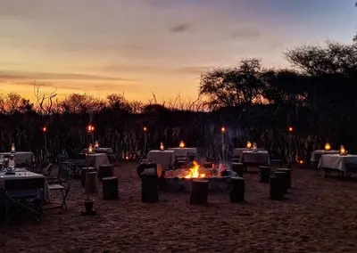 a group of tables and chairs with a fire at sunset at Finfoot Lake Reserve by Dream Resorts in Vaalkop Dam