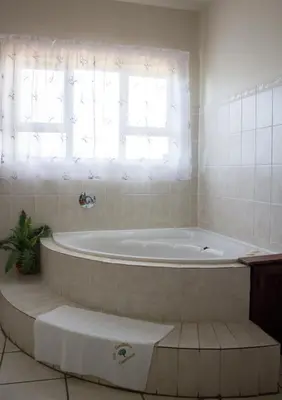 a bath tub in a bathroom with a window at Villa Too Kruger Lodge in Komatipoort
