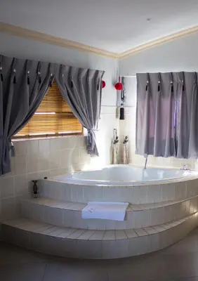 a large bath tub in a bathroom with a window at Villa Too Kruger Lodge in Komatipoort