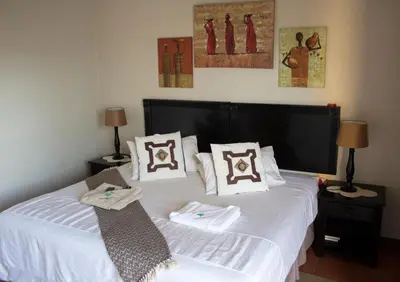 a bedroom with two beds with white sheets and pillows at Villa Too Kruger Lodge in Komatipoort