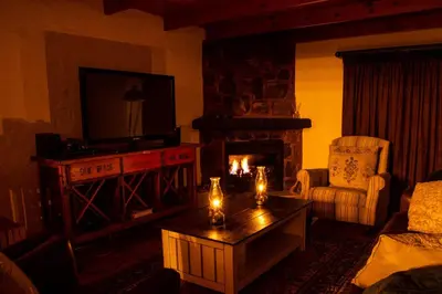 a living room with a fireplace and a table with candles at Critchley Hackle - Managers Cottage in Dullstroom