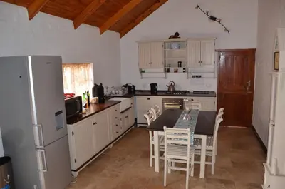 a kitchen with white cabinets and a table and chairs at Critchley Hackle - Managers Cottage in Dullstroom