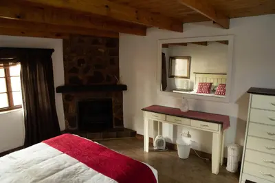 a bedroom with a bed and a mirror and a fireplace at Critchley Hackle - Managers Cottage in Dullstroom