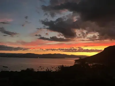 a sunset over a body of water with mountains at Thatch View in Hartbeespoort