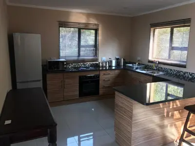 a kitchen with wooden cabinets and a black counter top at Thatch View in Hartbeespoort