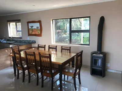 a dining room with a wooden table and a wood stove at Thatch View in Hartbeespoort