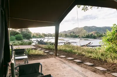 a tent with chairs and a view of a river at Limpokwena Nature Reserve in Tokio