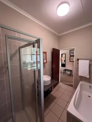 a bathroom with a shower and a sink and a tub at Big Tree Midrand in Midrand