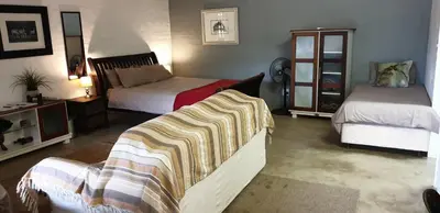 a bedroom with two beds and a couch with a blanket at Numbi Hills Self-Catering in Hazyview