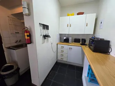 a small kitchen with white cabinets and a counter top at Hills and Dales Accommodation in Lanseria