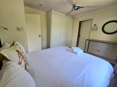 a bedroom with a white bed with a ceiling fan at Hills and Dales Accommodation in Lanseria