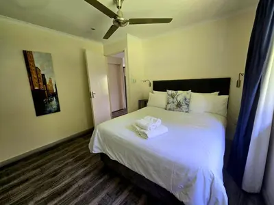 a bedroom with a bed with two towels on it at Hills and Dales Accommodation in Lanseria